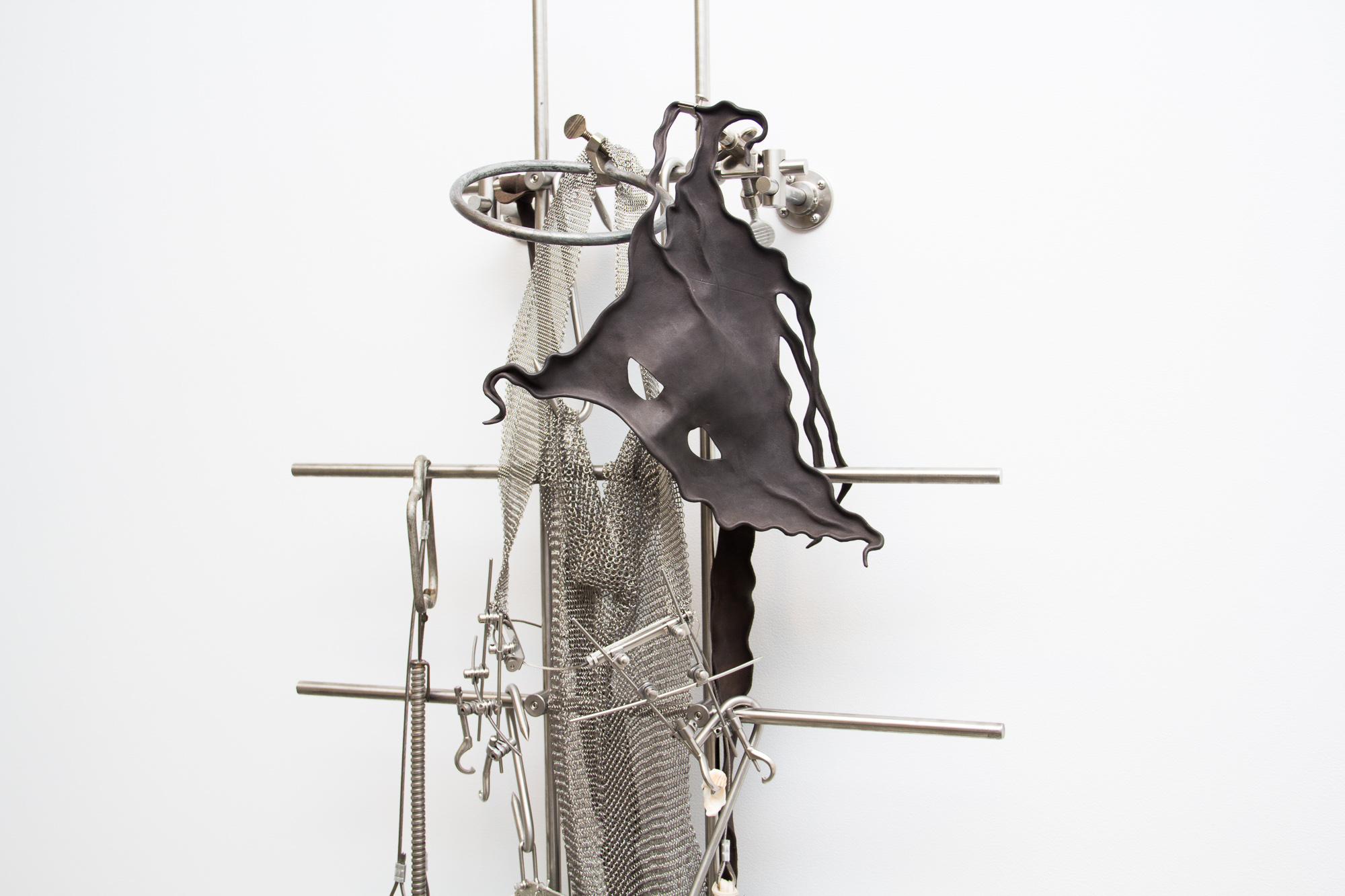 Elaine Cameron-Weir, zone in which the shell material was essentially solid and an axial zone in which cup-shaped cavities remain in the camerae; with growth, the axial zone widens adorally at the expense of the peripheral zone (detail), 2019, stainless steel, aluminum, pewter, parachute silk, parachute harness clips and ripcord hardware, laboratory clamps, orthopedic jaw fixation hardware, leather, shells, 79.50h x 24w x 8d in.