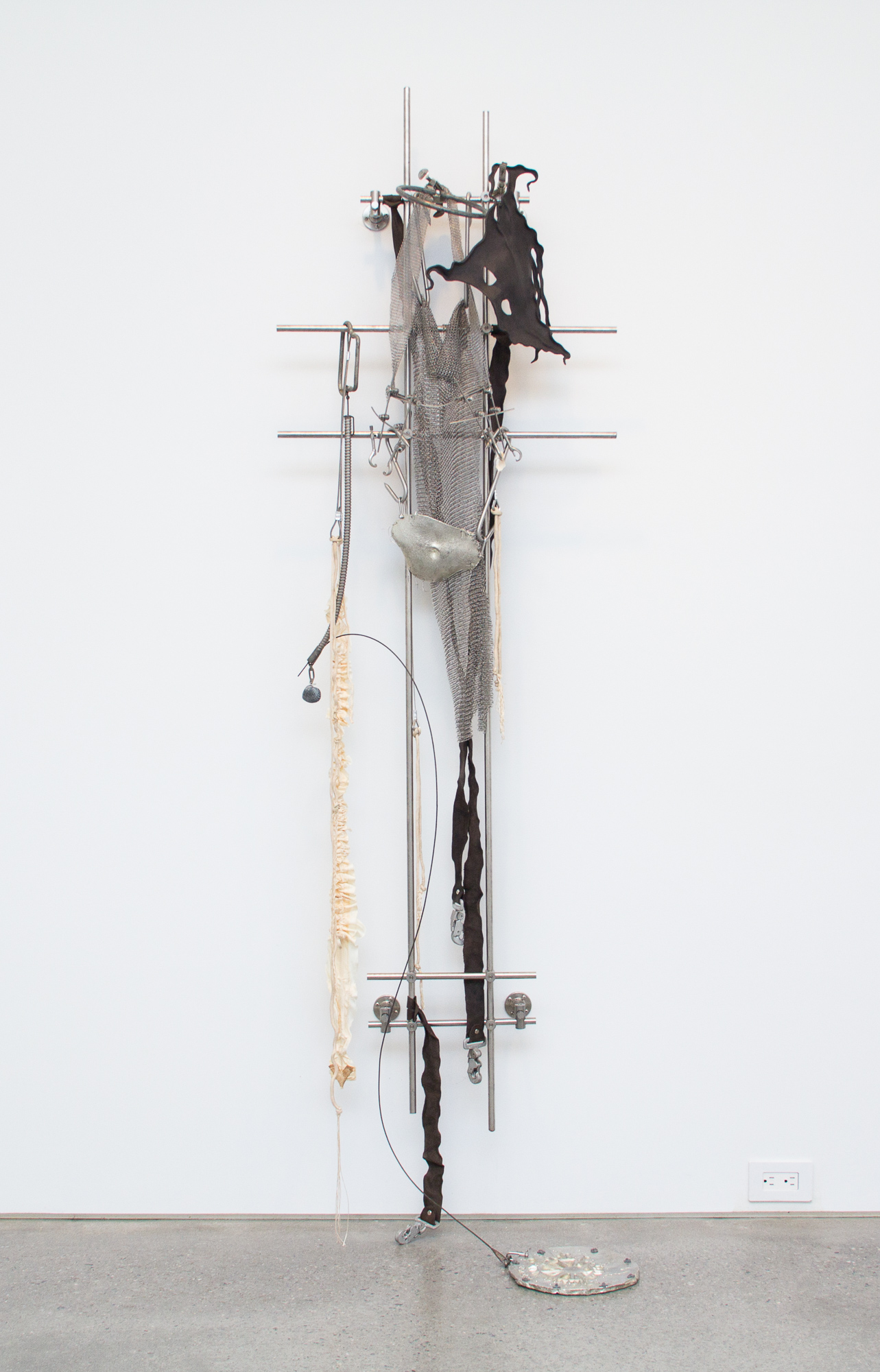 Elaine Cameron-Weir, zone in which the shell material was essentially solid and an axial zone in which cup-shaped cavities remain in the camerae; with growth, the axial zone widens adorally at the expense of the peripheral zone, 2019, stainless steel, aluminum, pewter, parachute silk, parachute harness clips and ripcord hardware, laboratory clamps, orthopedic jaw fixation hardware, leather, shells, 79.50h x 24w x 8d in.